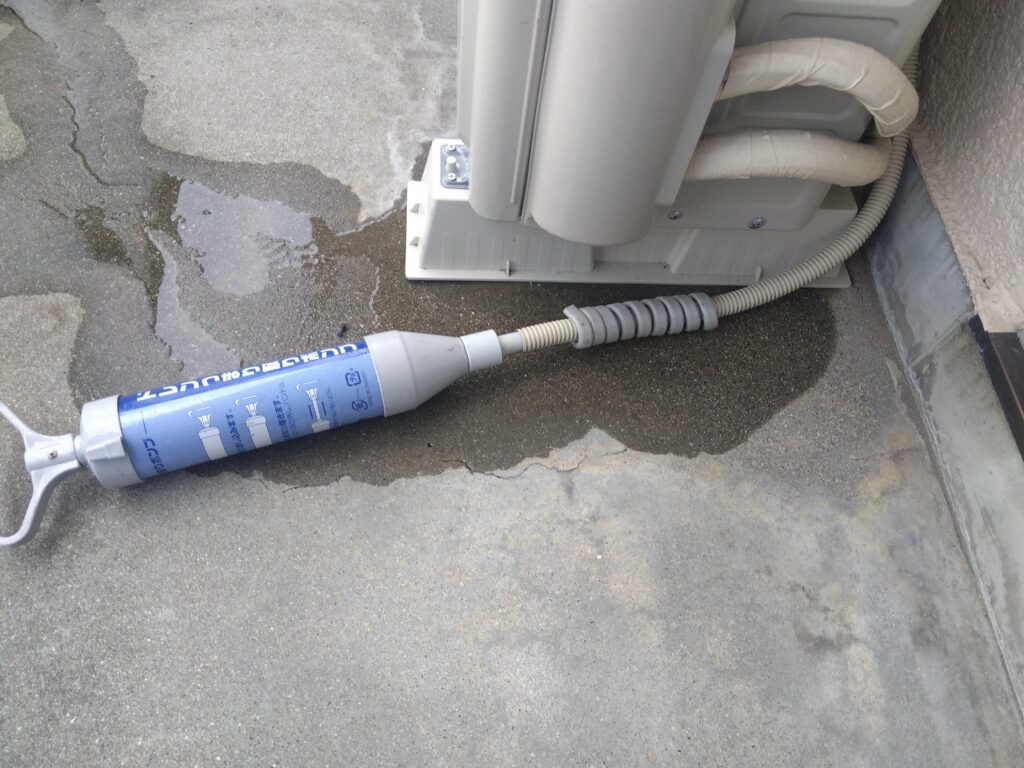 サクションポンプでドレンホースに詰まったゴミを吸い出して水漏れを改善させる